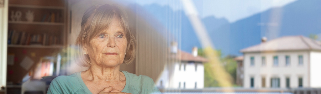 Mujer mirando por la ventana de una residencia de ancianos 